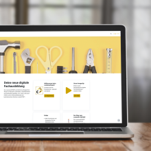 Laptop mit geöffneter Website zur digitalen Fachausbildung, im Hintergrund Werkzeuge auf gelbem Hintergrund